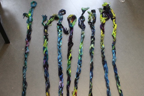 Multi colored warp chains laid out on a gray floor in random order