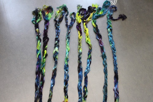 The same multi colored chains, laid out on a gray floor, in a different order