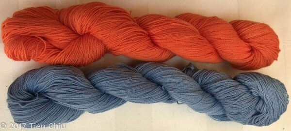 two twisted skein of yarn, one is a grayish blue, and one is a deep orange