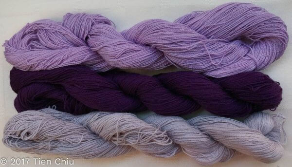 three twisted skeins of yarn, in different values of purple