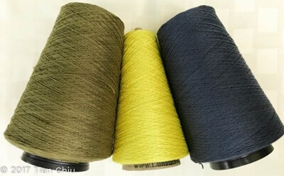 three cones of yarn in olive, yellow-green and navy blue