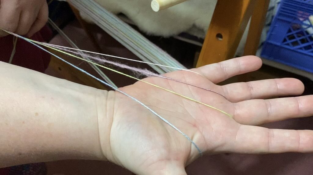 Janet holding her weaving yarn warp in her hand
